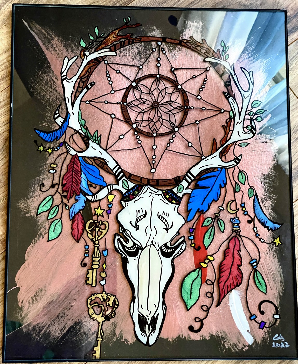 A deer skull and dreamcatcher with feathers and a hanging gold key